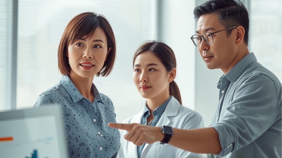 歯科医院のスタッフがパソコンの画面を見ながらサイト構成を確認している様子。日本人スタッフ、清潔な受付の雰囲気
